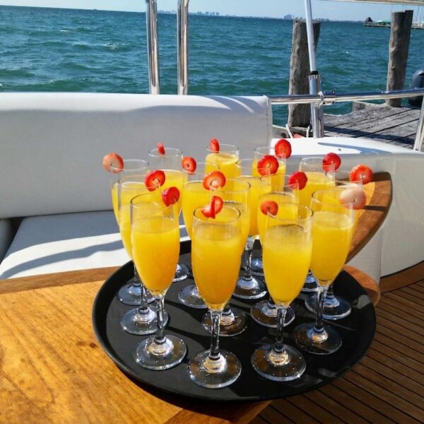 Charola de mimosas frescas decoradas con fresas servidas en una cubierta de teca del yate con vista a la marina de Canc&uacute;n.