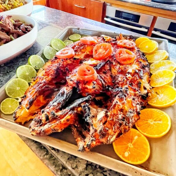 Pescado entero asado decorado con jitomate, lim&oacute;n y rodajas de naranja junto a fajitas en la barra de la cocina del yate.