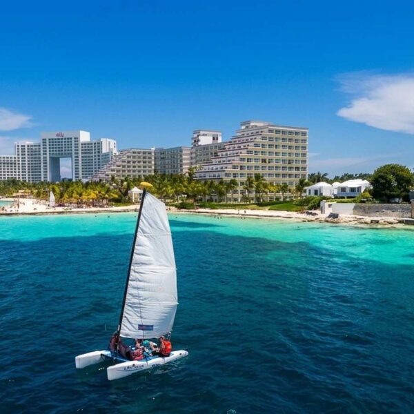 Peque&ntilde;o catamar&aacute;n de vela navegando por el Caribe turquesa frente a la zona hotelera de Canc&uacute;n, ideal para divertirse con water toys en un tour de yate.
