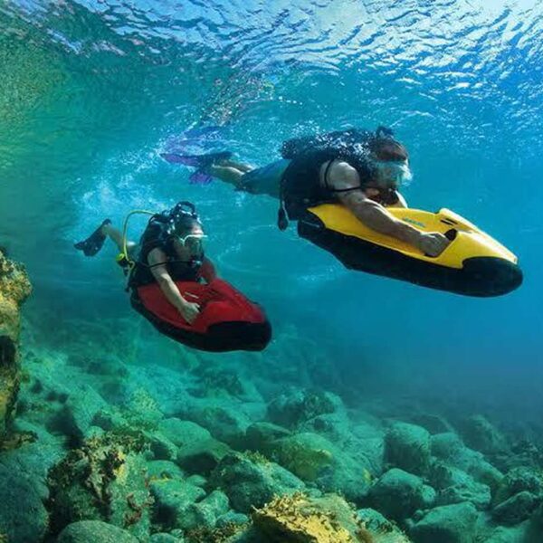 Dos esnorqueleros con seabob subacu&aacute;ticos sobre un arrecife rocoso, explorando la colorida vida marina del Caribe con m&aacute;scara y equipo.