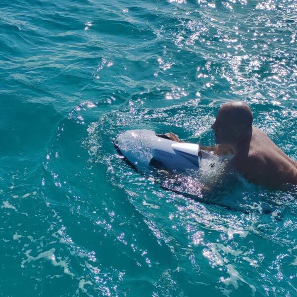 Nadador atravesando aguas turquesas brillantes sujetando un seabob subacu&aacute;tico, un water toy divertido durante una salida en yate en Canc&uacute;n.