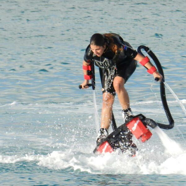 Mujer haciendo flyboard sobre el agua en una tabla de vuelo con propulsi&oacute;n de agua durante una sesi&oacute;n de deportes acu&aacute;ticos llena de acci&oacute;n en Canc&uacute;n.