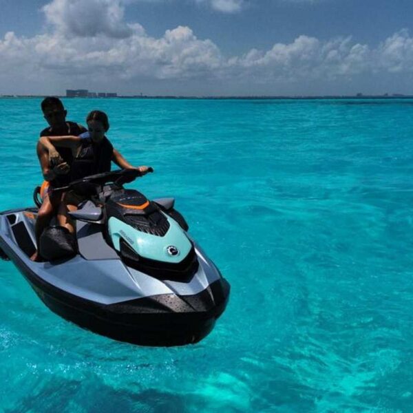 Pareja paseando en un jet ski Sea-Doo turquesa por aguas turquesas cristalinas del Caribe cerca de Canc&uacute;n, uno de los mejores water toys para tours de yate.