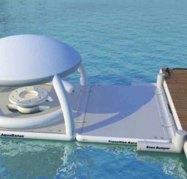 AquaBanas inflatable floating dock with shaded cabana cover and a transition platform that attaches to a luxury yacht's swim deck, creating an on-water lounge extension.