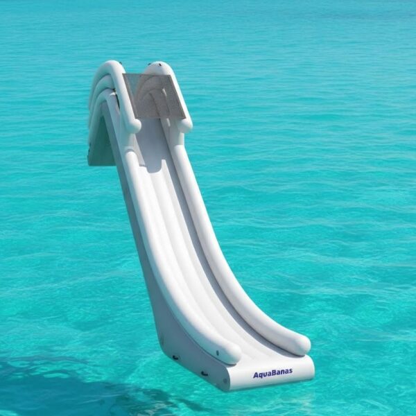 Inflatable AquaBanas water slide mounted to a yacht's side, descending into bright turquoise Caribbean shallows for kids and adults to slide aboard.
